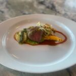 Stuffed Lamb Leg with Pistachio, Greens, and Apricot served with natural jus, fondant celery root with pistachio pesto, saffron tomato, red & green harissa, and butternut squash with mustard and pink peppercorns