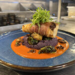 prosciutto-wrapped monkfish with purple yam purée and Brussels sprouts on smoked tomato coulis