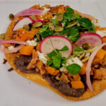 Autumn Chorizo and Squash Tostada | Crisp Corn Tortilla, Black Bean Spread, Crumbled Chicken Chorizo, Chili-Roasted Squash, Crunchy Pickled Red Onion and Radish Salad, Crumbled Cotija Cheese, Pumpkin Seeds